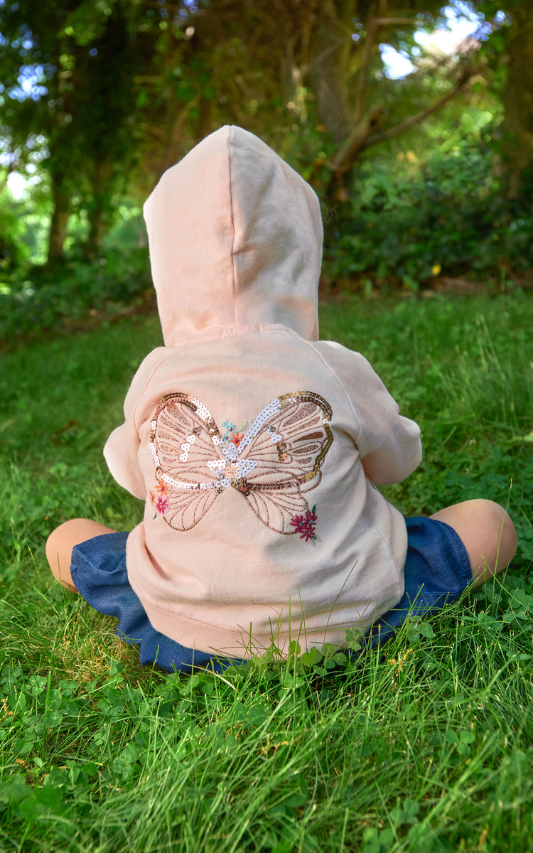 Back of young girl wearing pink zip-up hoodie with embroidered butterfly wings