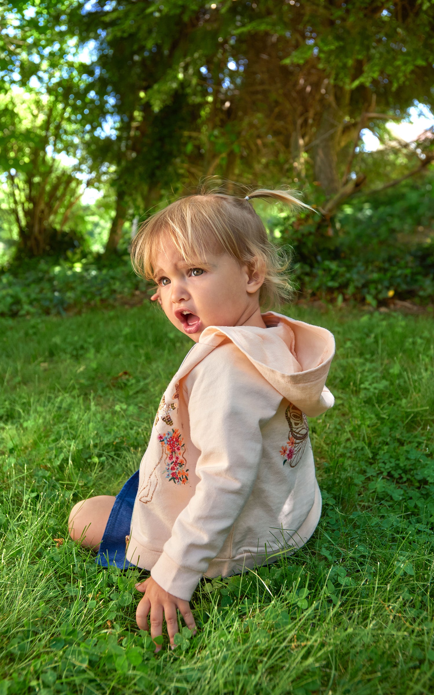 Young girl wearing pink zip-up hoodie with sparkly embroidered unicorn