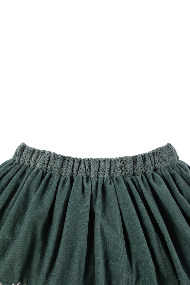 close up view of green velvet skirt with floral detail 