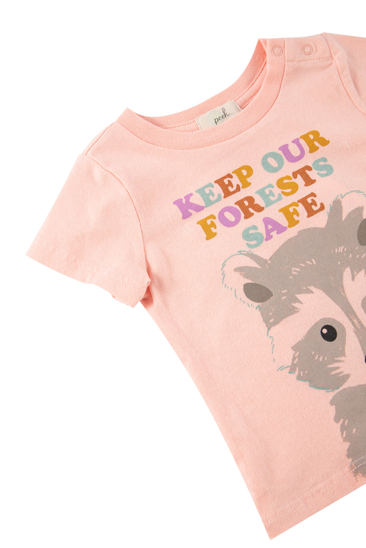 Close up of pink t-shirt with illustrated raccoon and 'keep our forests safe' text