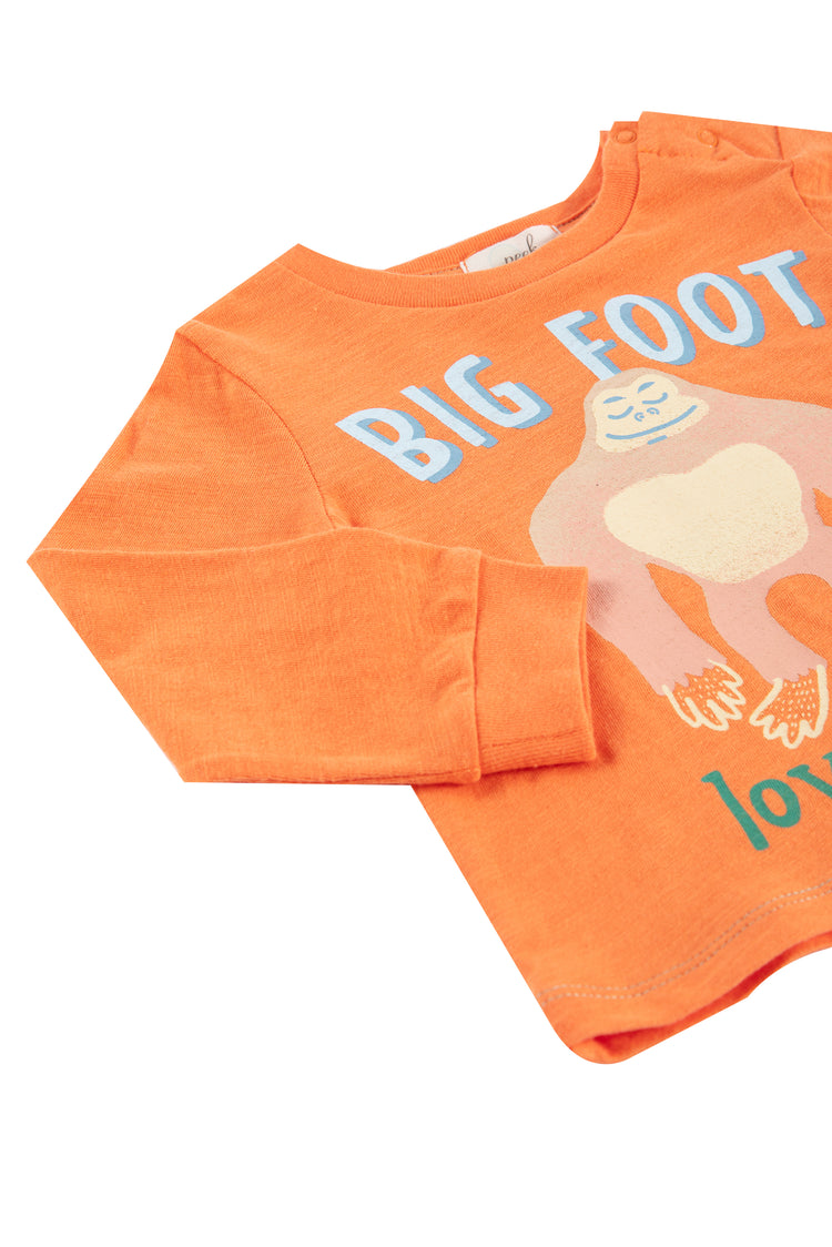 Close up side view of orange long sleeve top featuring bigfoot themed artwork and text "bigfoot loves me"